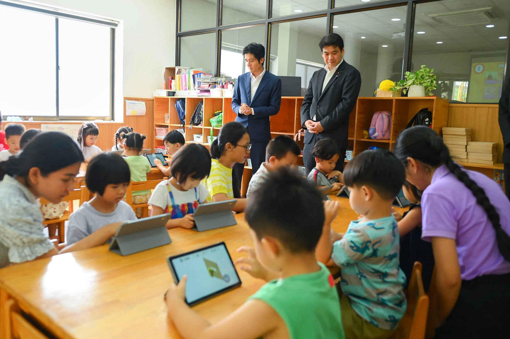 教室でタブレット学習に取り組む子どもたちと大人