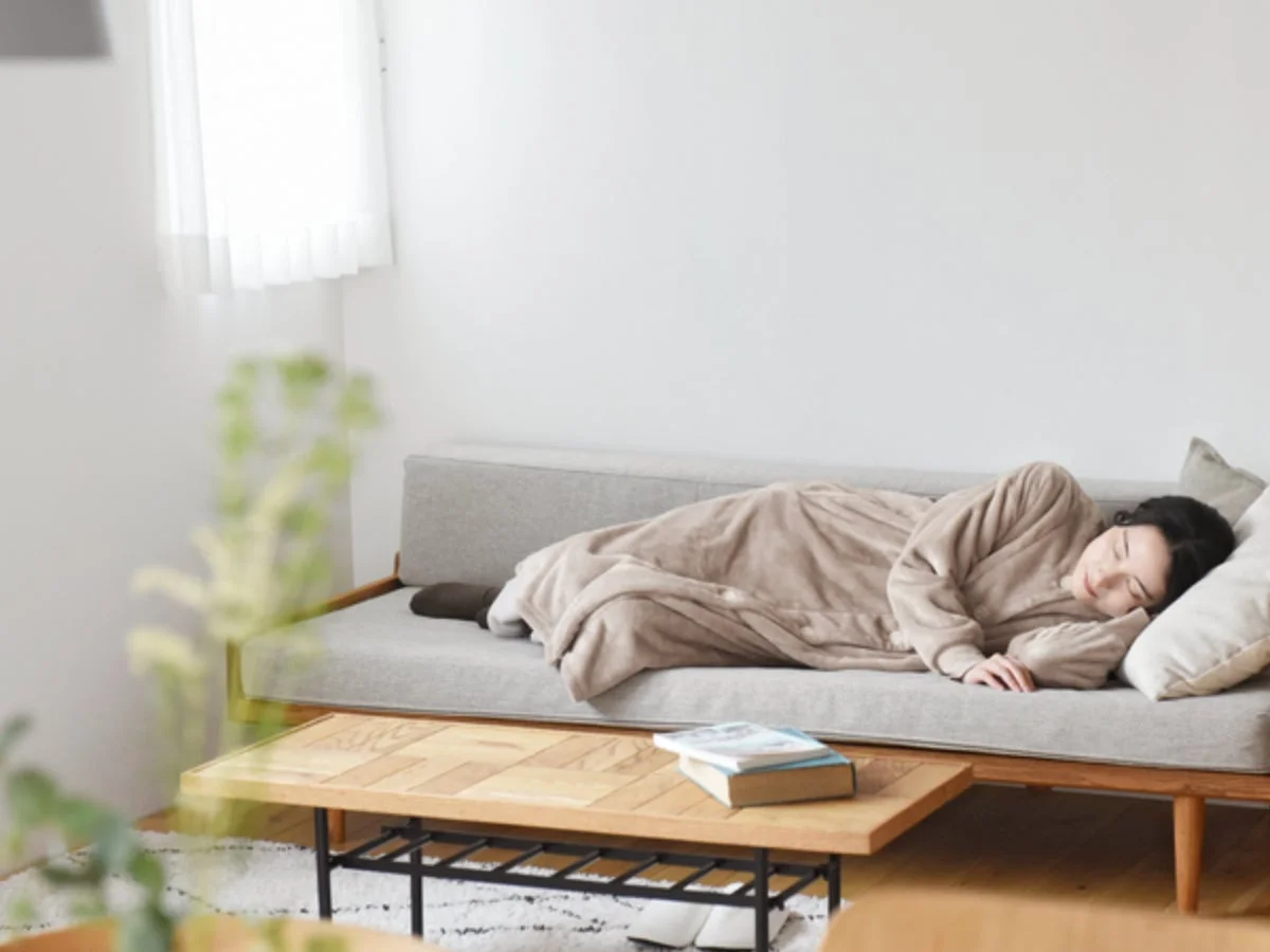 ソファで着る毛布にくるまってくつろぐ女性