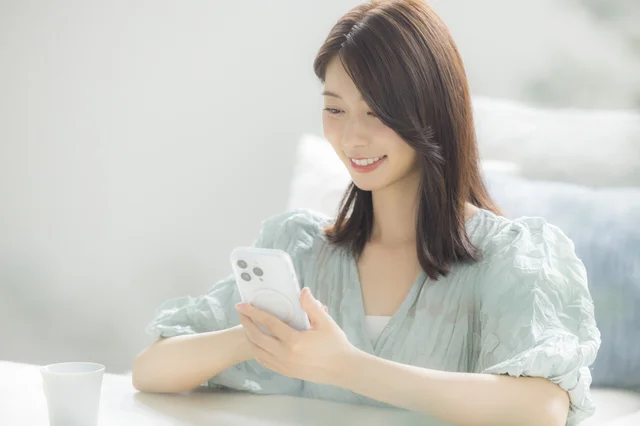 スマートフォンでオンラインレッスンを受講する女性の画像