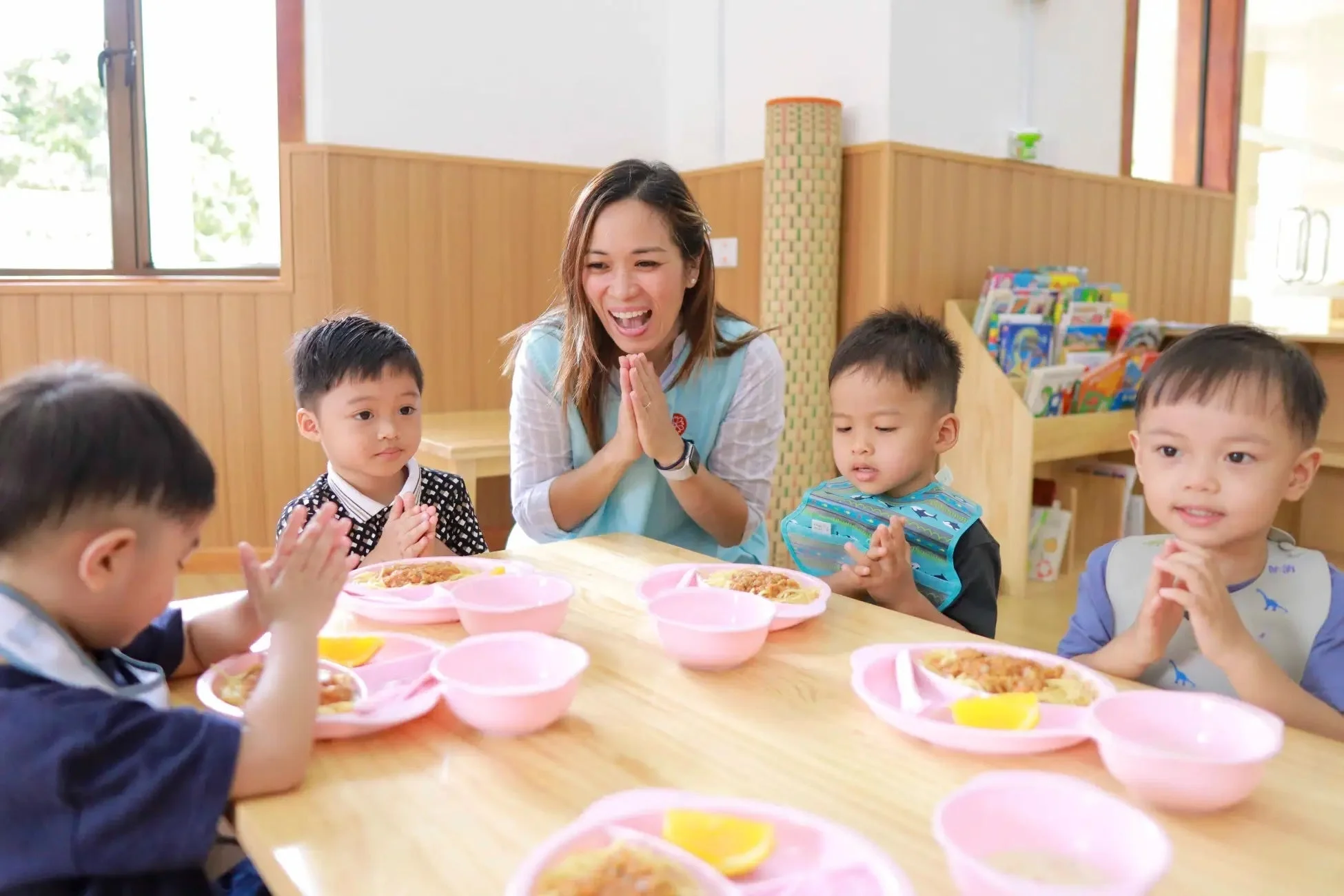 食事の前に手を合わせる先生と子どもたち