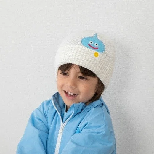 白いビーニー帽と水色のジャケットを着て笑顔を見せる子供の姿。