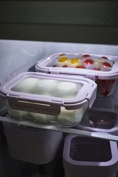 冷蔵庫の棚に、白い丸い食材と赤・黄色のミニトマトが入った保存容器が置かれている様子