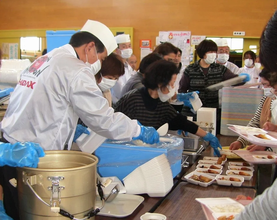 マスクと手袋を着用し食事の配給を行う人々