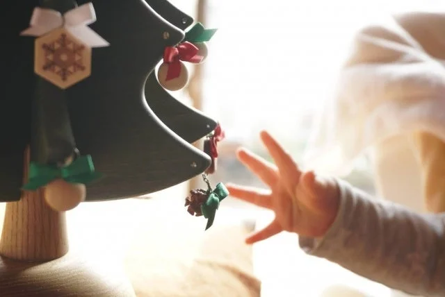 クリスマスツリーの飾りを触ろうと手を伸ばす子供の手