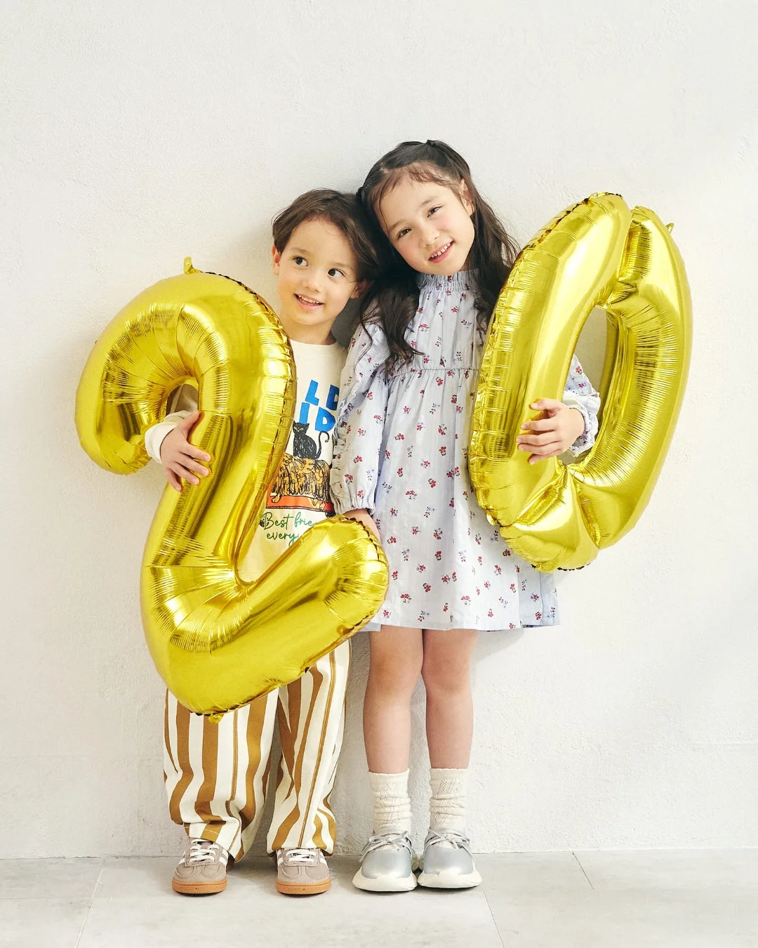 笑顔の男の子と女の子が「20」の風船を持つ